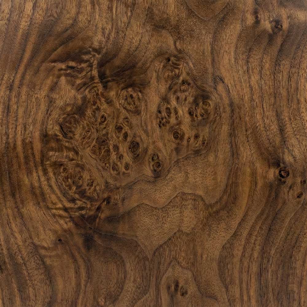A close-up of a Walnut Burl surface, featuring a rich medium-brown background agitated by wild, swirling grain patterns and dense groupings of dark burl eyes.