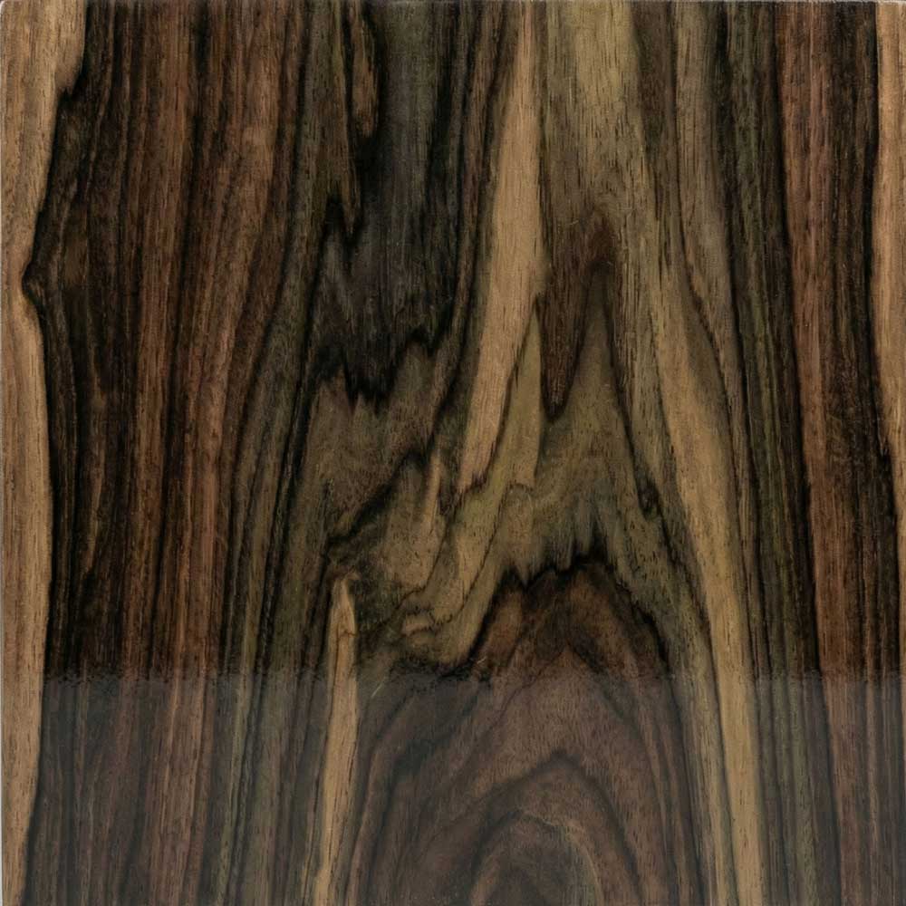 A detailed view of a Ziricote veneer, showing a dark brown to black background illuminated by dramatic, cloud-like grain patterns in lighter grey and greenish-brown tones.